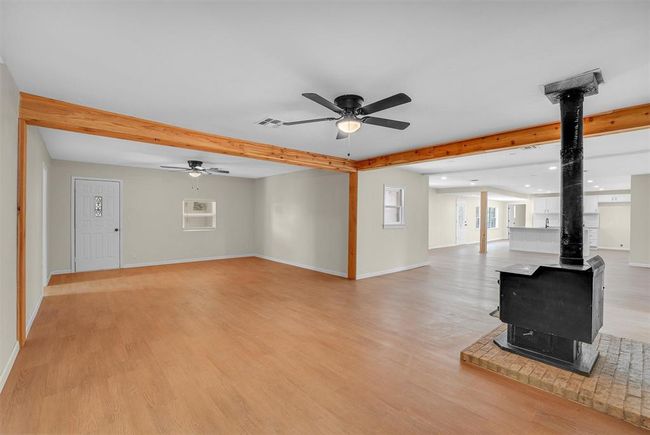 Basement with a wood stove, ceiling fan, and light wood-type flooring | Image 16