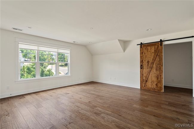 Additional living space featuring wood finished floors, a barn door, lofted ceiling, and recessed lighting | Image 25