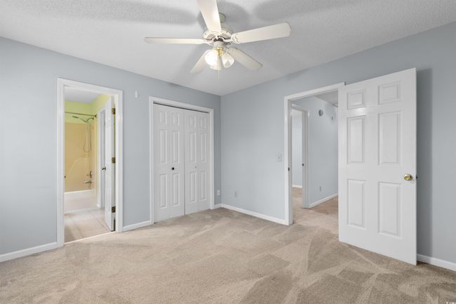 Unfurnished bedroom with carpet floors, a closet, connected bathroom, a textured ceiling, and a ceiling fan | Image 15