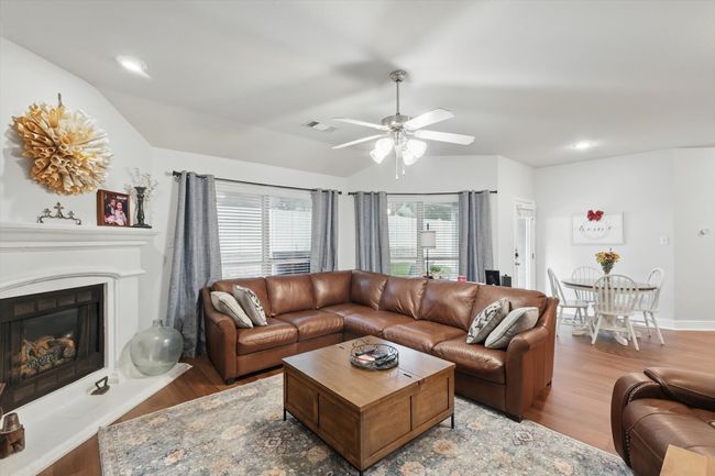 Living room featuring lofted ceiling, wood finished floors, ceiling fan, a fireplace with raised hearth, and recessed lighting | Image 21