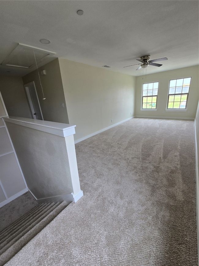Unfurnished room featuring attic access, carpet floors, ceiling fan, and baseboards | Image 18