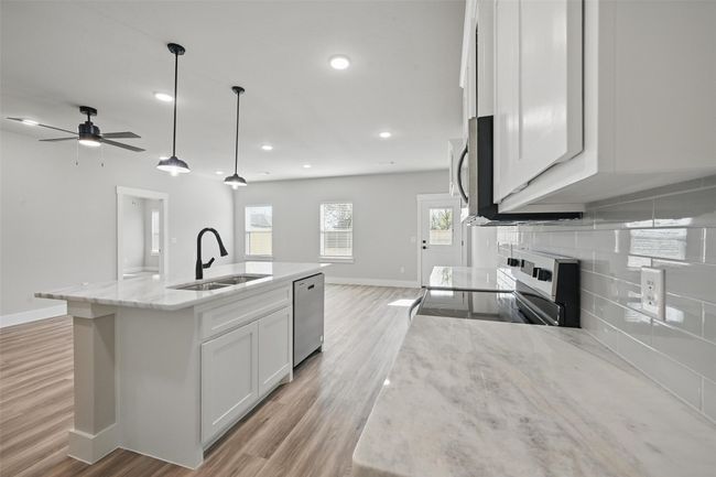Kitchen with open floor plan, white cabinets, a sink, and appliances with stainless steel finishes | Image 7