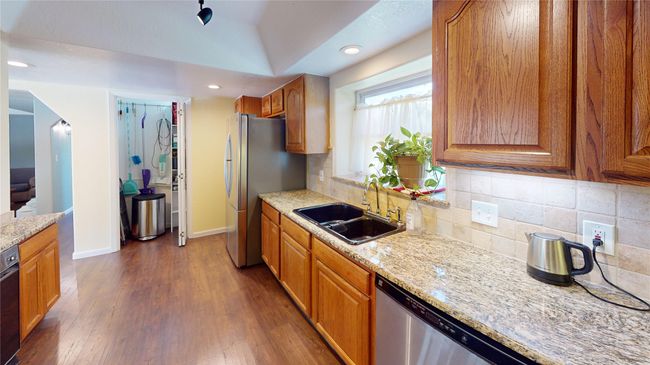 Kitchen featuring light stone countertops, decorative backsplash, stainless steel appliances, dark wood-style flooring, and recessed lighting | Image 11