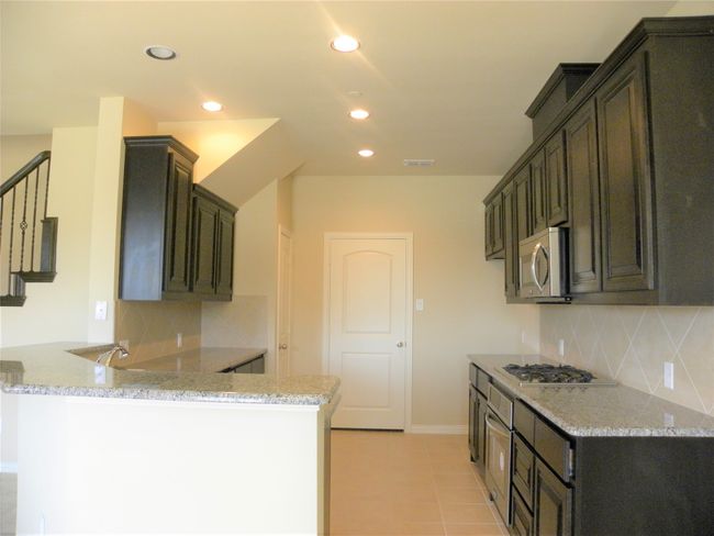 Kitchen with stainless steel appliances, a peninsula, backsplash, light stone countertops, and recessed lighting | Image 10