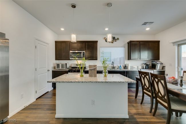 Kitchen with dark wood-style flooring, dark brown cabinets, appliances with stainless steel finishes, and visible vents | Image 24