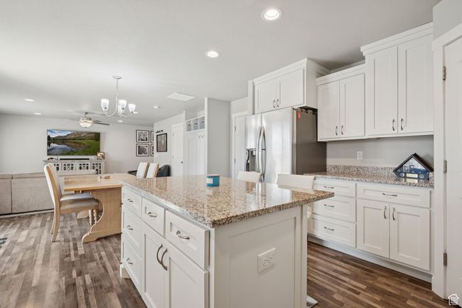 Kitchen with stainless steel fridge with ice dispenser, a chandelier, dark wood-style floors, a kitchen island, and white cabinetry | Image 12