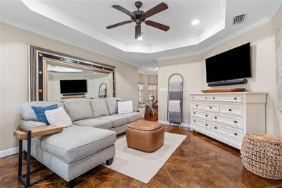 Tiled living room with ceiling fan, a tray ceiling, and crown molding | Image 2