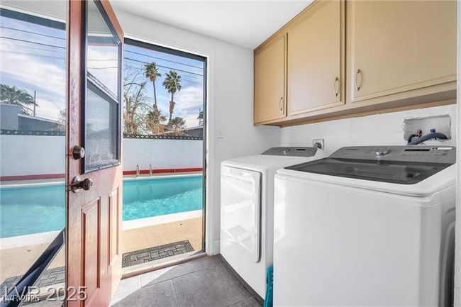 Laundry room featuring cabinet space, washing machine and clothes dryer, and dark tile patterned flooring | Image 18
