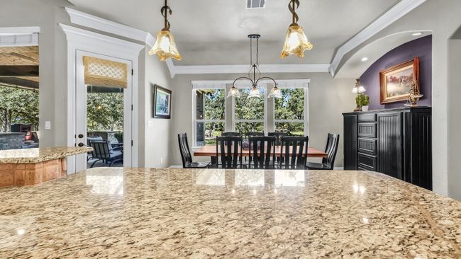 Kitchen featuring ornamental molding, light stone counters, a chandelier, and hanging light fixtures | Image 19