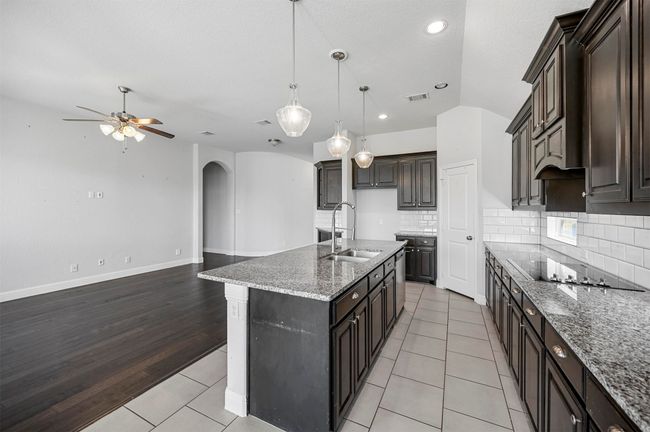 Kitchen with visible vents, arched walkways, a ceiling fan, black electric cooktop, and a sink | Image 16