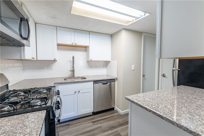 Kitchen with a sink, light wood-style floors, tasteful backsplash, appliances with stainless steel finishes, and white cabinetry | Image 7