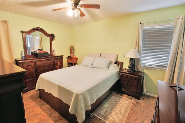 Bedroom featuring a ceiling fan, a textured ceiling, baseboards, and wood finished floors | Image 14