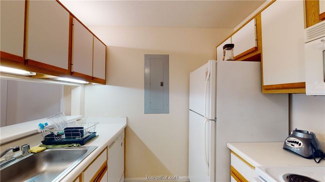 Kitchen featuring electric panel, white appliances, white cabinets, and sink | Image 7