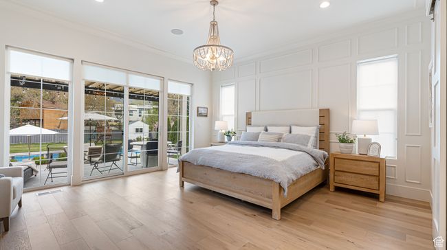 Bedroom featuring light wood-type flooring, a decorative wall, crown molding, a chandelier, and access to outside | Image 12