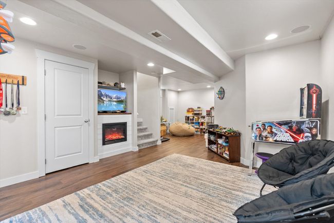 Fully finished basement featuring a family room with wood-look vinyl floors, recessed lighting, and electric fireplace | Image 28