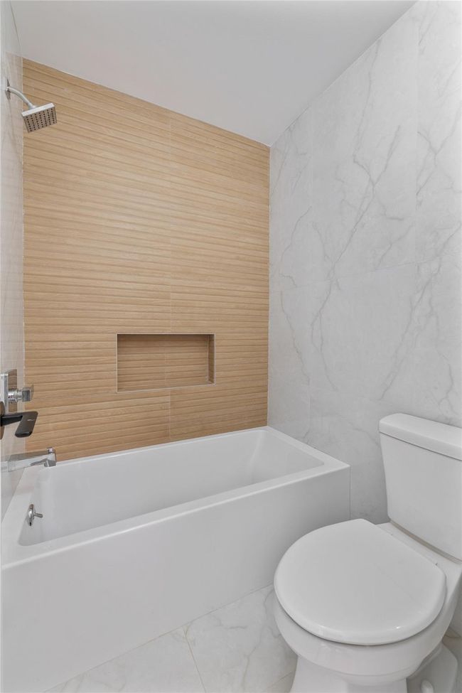 Bathroom with marble finish floor, tile walls, and toilet | Image 28