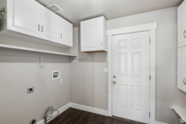 Laundry room featuring washer hookup, dark wood-type flooring, cabinets, and hookup for an electric dryer | Image 25