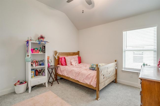 Bedroom featuring light colored carpet, lofted ceiling, baseboards, and a ceiling fan | Image 28