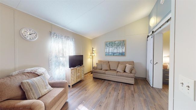 Living area featuring lofted ceiling, a barn door, light wood finished floors, and baseboards | Image 15