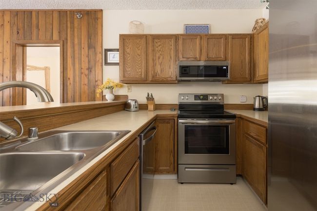 Kitchen featuring a textured ceiling, stainless steel appliances, and sink | Image 16