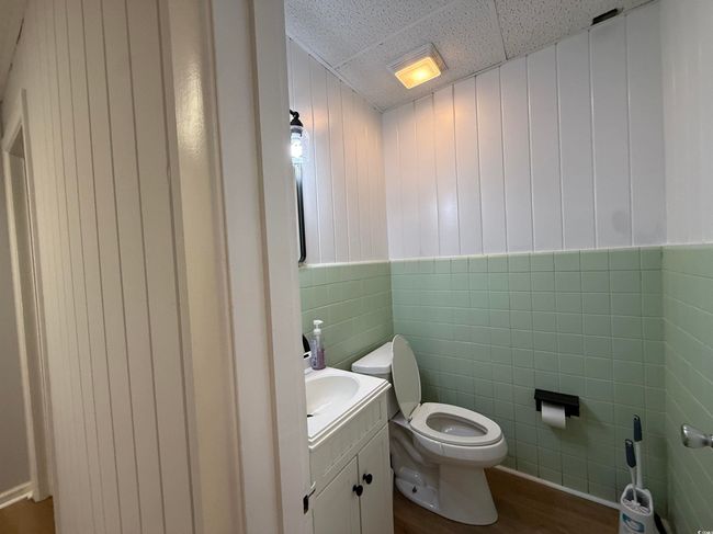 Bathroom with tile walls, vanity, wood finished floors, and wainscoting | Image 9