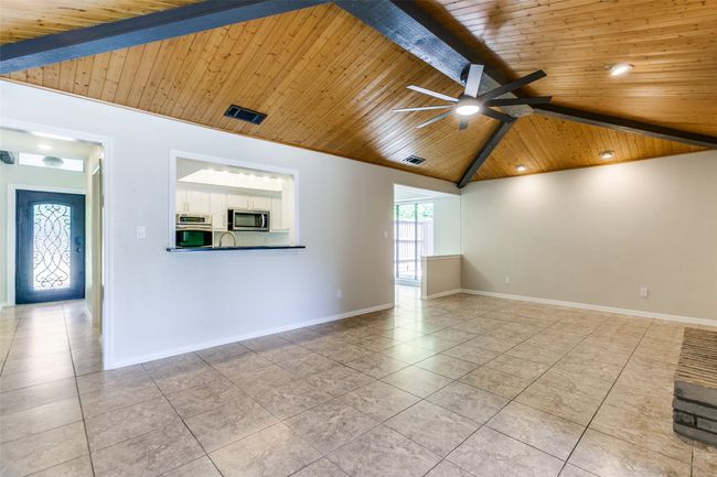 Unfurnished living room with wood ceiling, tile patterned flooring, and ceiling fan | Image 6