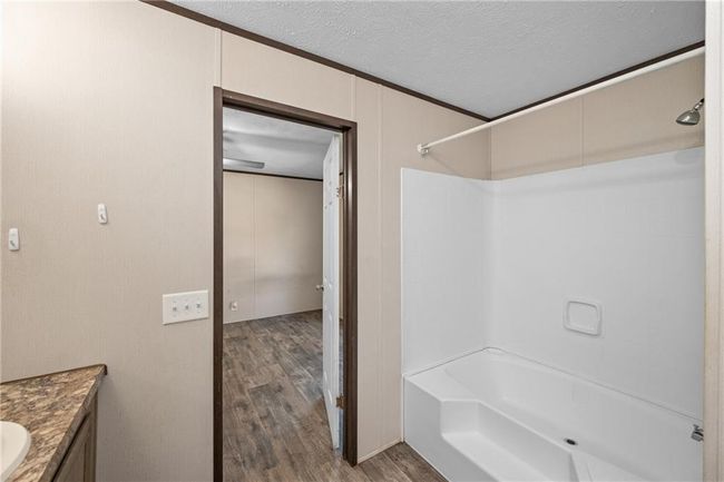 Bathroom with wood finished floors, tub / shower combination, vanity, and a textured ceiling | Image 28