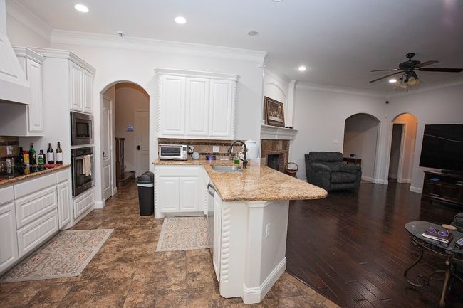 Kitchen with arched walkways, stainless steel appliances, crown molding, white cabinetry, and tasteful backsplash | Image 6