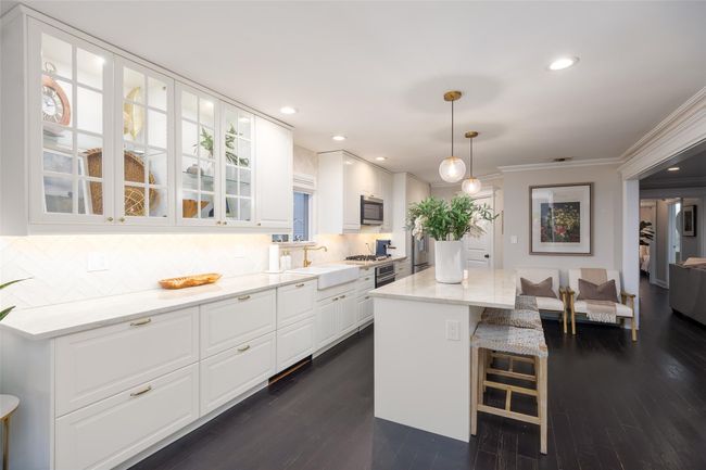 Kitchen featuring white cabinets, crown molding, a breakfast bar, and a sink | Image 16