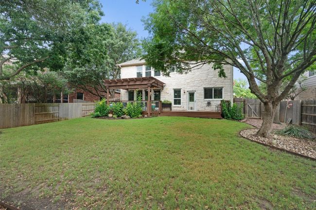 Rear view of house with stone siding, a pergola, and a deck | Image 34