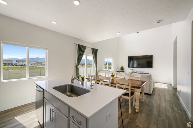 Kitchen featuring a sink, stainless steel dishwasher, dark wood-style floors, baseboards, and a center island with sink | Image 14