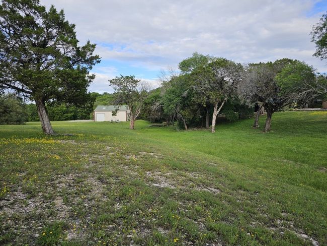 View of 40'x40' Garage/Shop Building on the property beyond the trees behind the home. This view is from the edge of the property. Note the 30'x40' Concrete Pad behind the Building. The previous owner used this pad to land his helicopter. This building, with it's tall roll-type door served as a hangar. | Image 36