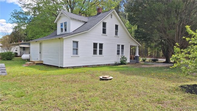 View of side of home featuring heating fuel, a shingled roof, a chimney, and a lawn | Image 47