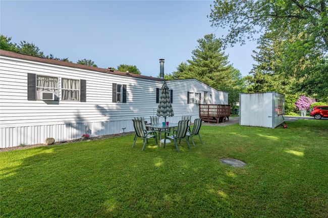 View of grassy yard featuring cooling unit and a wooden deck | Image 18