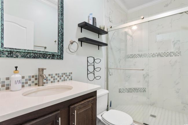 Full bathroom with ornamental molding, toilet, a marble finish shower, backsplash, and vanity | Image 13