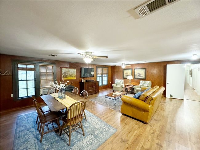 Dining room with wood finished floors, wooden walls, a ceiling fan, and visible vents | Image 6