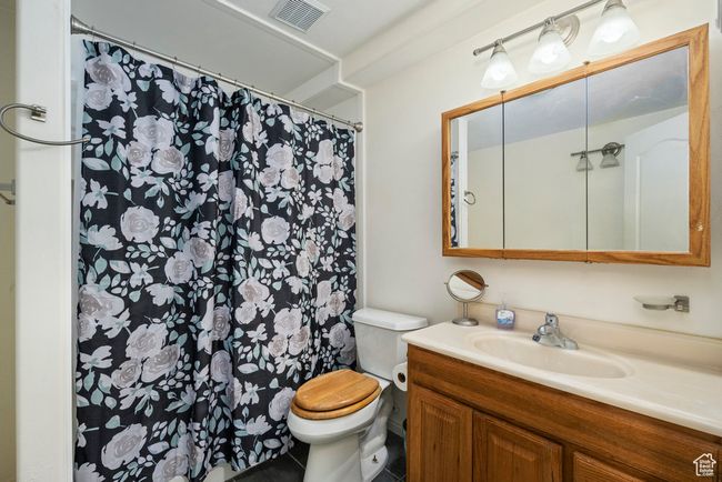 Full bath with vanity, toilet, tile patterned floors, a shower with curtain, and visible vents | Image 39