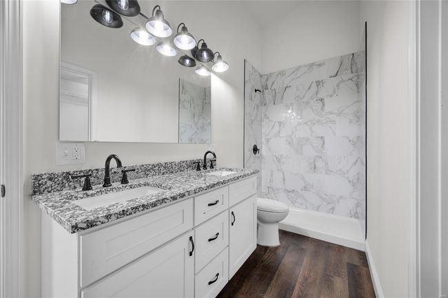 Full bathroom with a sink, a tile shower, double vanity, and wood finished floors | Image 40