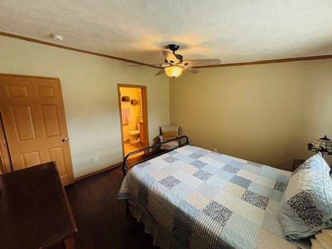 Bedroom featuring crown molding, dark wood-style flooring, ceiling fan, and ensuite bathroom | Image 14