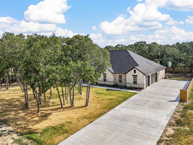 View of front of home with a shingled roof, stone siding, and a front lawn | Image 6