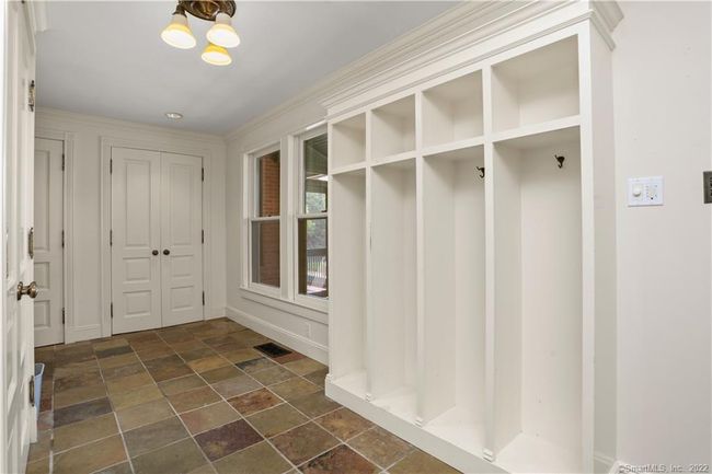 MUDROOM // Located off the attached garage sits one of the four laundry locations and includes cubbies and multiple closets. Access to screened porch, half bath and close proximity to elevator and playroom. | Image 13