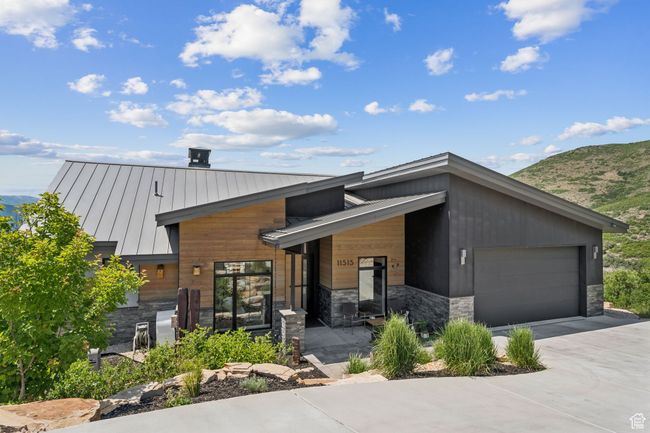 Contemporary home featuring a standing seam roof, stone siding, a mountain view, driveway, and a metal roof | Image 71