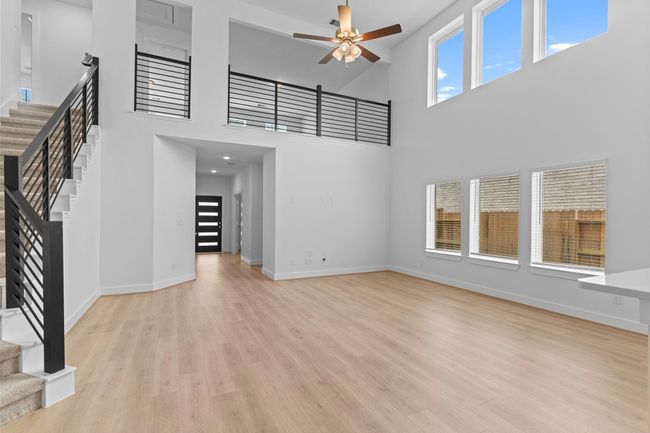 The two-story family room captures natural light beautifully through its full wall of windows, making the space feel bright, welcoming, and perfect for any style of decor. **Image Representative of Plan Only and May Vary as Built**. | Image 25