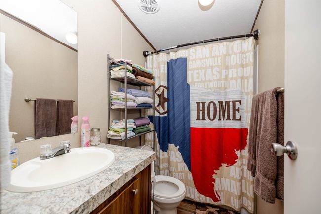 Full bath featuring a shower with shower curtain, vanity, toilet, visible vents, and lofted ceiling | Image 12