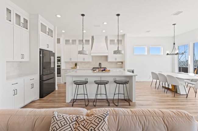 Kitchen featuring stainless steel appliances, custom exhaust hood, open floor plan, tasteful backsplash, and light countertops | Image 5
