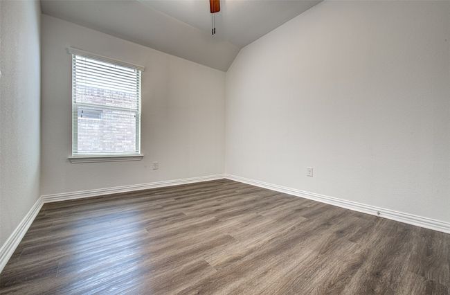 Spare room featuring vaulted ceiling, ceiling fan, and dark wood-style flooring | Image 11