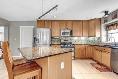 Lovely kitchen offers plentiful cabinetry, solid surface counters, tile backsplash, stainless appliances, and more! | Image 2