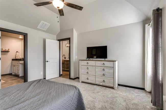 Bedroom with lofted ceiling, baseboards, ensuite bath, and visible vents | Image 23