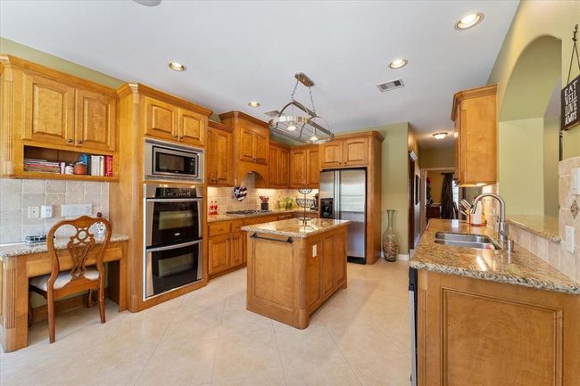 Large kitchen overlooking the den, with prep island, desk area, double oven, stainless steel appliances | Image 10