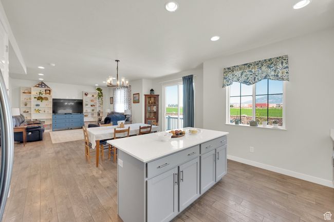 Kitchen featuring light wood-style flooring, a center island, recessed lighting, light countertops, and a chandelier | Image 8